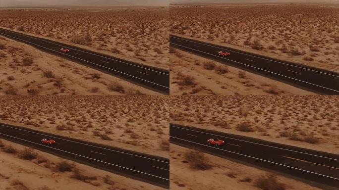 鸟瞰图红色经典汽车在黄昏时沿着荒凉的沙漠路行驶，前灯开着