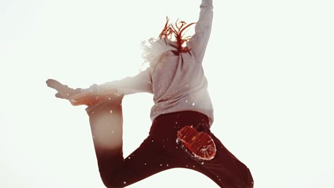 精力充沛的女人跳跃，在晴朗的天空中踢雪，超级慢动作