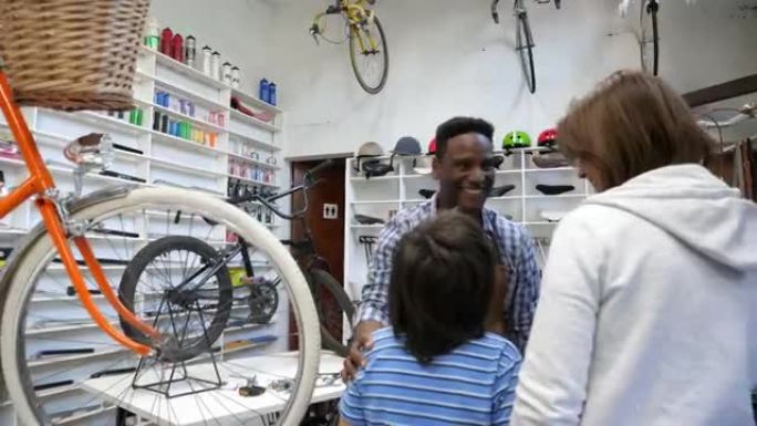 惊讶的小男孩骑着自行车买了他的第一辆自行车，妈妈看起来很高兴，推销员给他看了一辆自行车