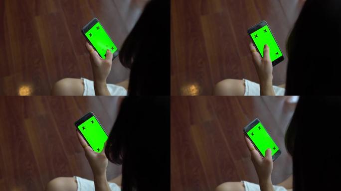 十几岁的女孩正在家里使用带有绿屏的智能手机