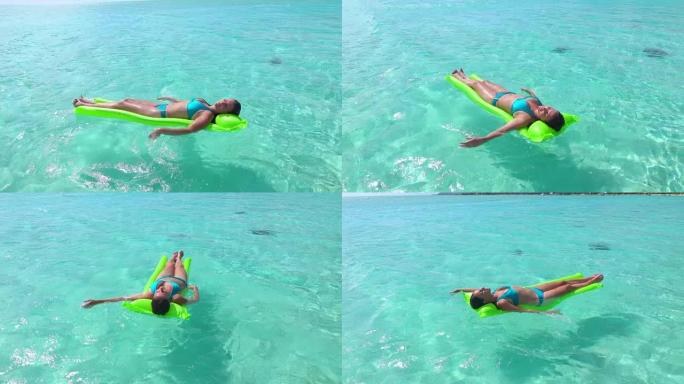 慢动作: 波拉波拉岛度假胜地美丽的翡翠泻湖中漂浮在水面上的充气充气床垫上穿着比基尼的快乐年轻女性