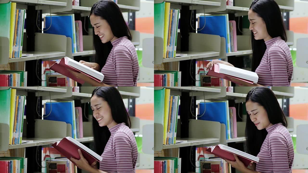 亚洲学生微笑着在图书馆看书。