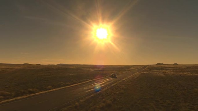空中: 黑色SUV汽车在空旷的州际公路上穿越阳光明媚的沙漠