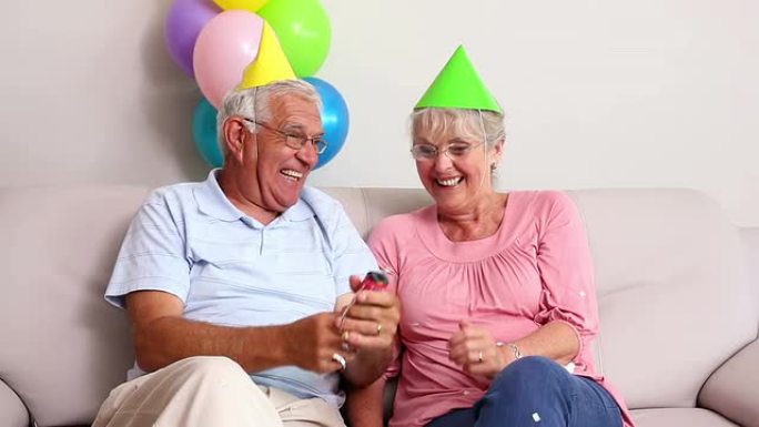 高级夫妇在沙发上庆祝生日