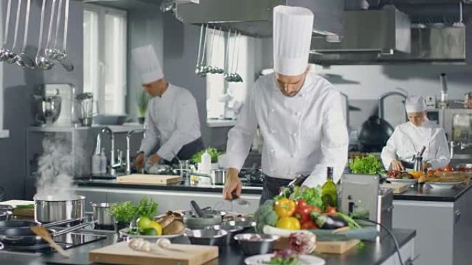 著名厨师和他的工作人员在一个大餐厅厨房工作。这个地方有干净的现代设计。