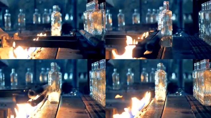 玻璃瓶在传送带上用火加热以进行巴氏杀菌。4K。