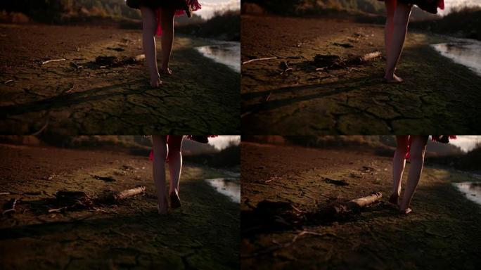 年轻女子赤脚走在山上破裂的土地上