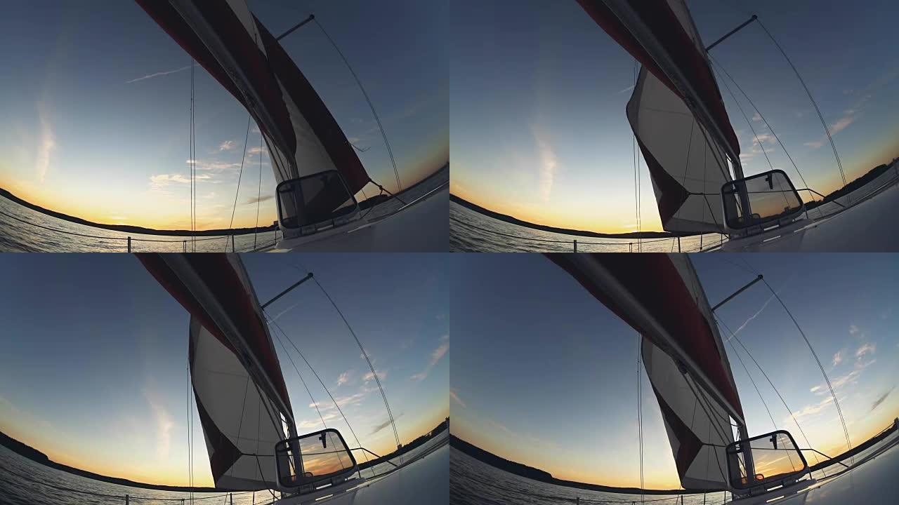 在开阔水域航行的游艇。风中风帆，船穿过水。日落时美丽的水景