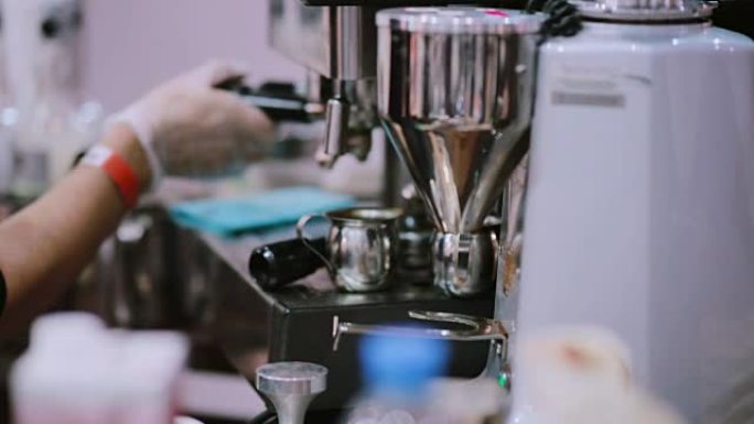 在电磨上研磨咖啡，然后咖啡师用咖啡机在咖啡吧里煮咖啡。特写