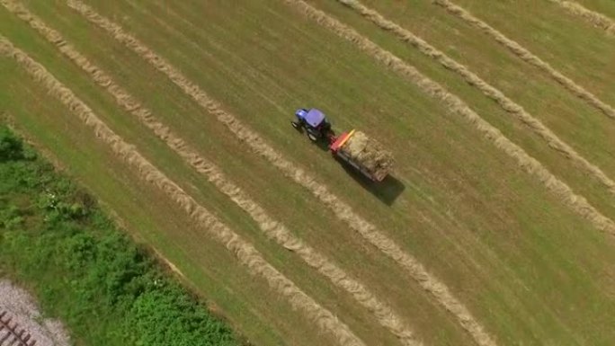 空中: 飞越农民用拖拉机捡起干草