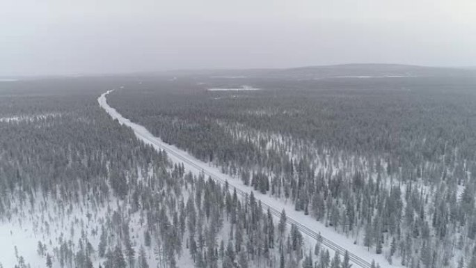 空中: 冬季白天，空旷的州际公路穿过白雪皑皑的森林