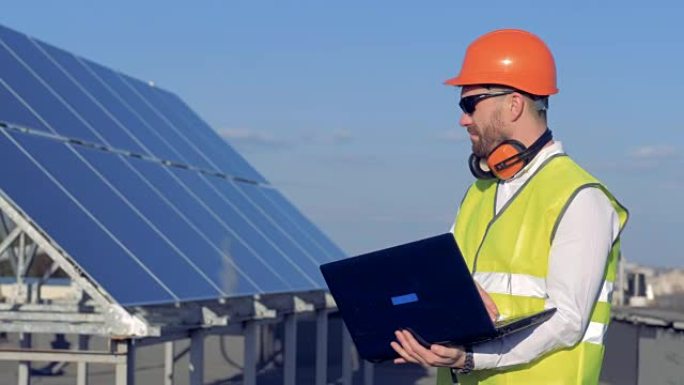 太阳能电池和一个男性建造师在附近使用笔记本电脑。生态节能理念。