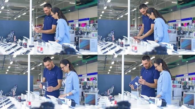 在电子商店中，美丽的年轻夫妇看着最新的平板电脑，他们考虑购买一台。商店很大，很明亮，并且拥有所有新设