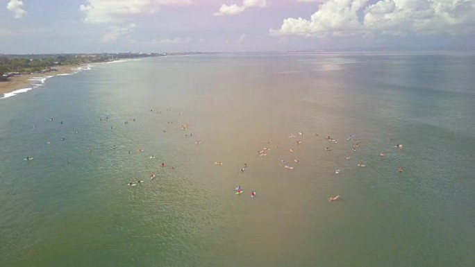 空中镜头耀斑: 巴厘岛长谷的沙滩上拥挤的冲浪者