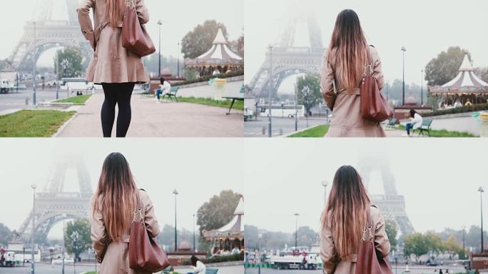 穿着法国风格的年轻女子步行到法国巴黎的埃菲尔铁塔。女孩看着著名的景象