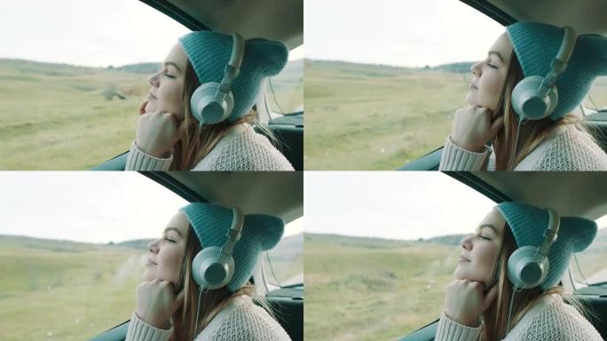 微笑的女孩在汽车后座上听音乐