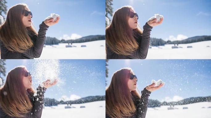 女人在冬天的风景中吹雪花