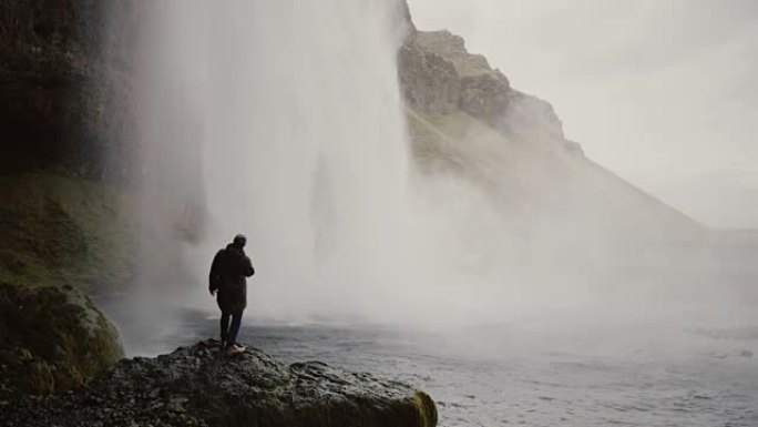 冰岛gljufragui瀑布附近有运动相机的年轻游客。男人看着北方大自然的著名景象