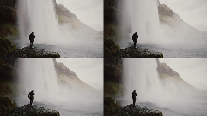 冰岛gljufragui瀑布附近有运动相机的年轻游客。男人看着北方大自然的著名景象