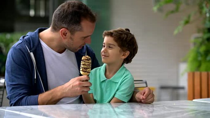 父亲和儿子在冰淇淋店分享冰淇淋看起来很开心