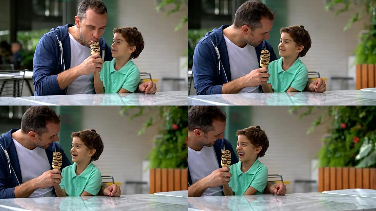 父亲和儿子在冰淇淋店分享冰淇淋看起来很开心
