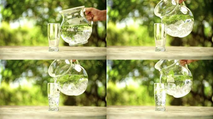 新鲜的薄荷水从水罐倒入玻璃杯中
