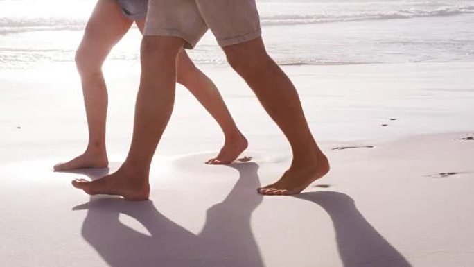 暑假期间，一对夫妇一起沿着海滩散步时的脚特写