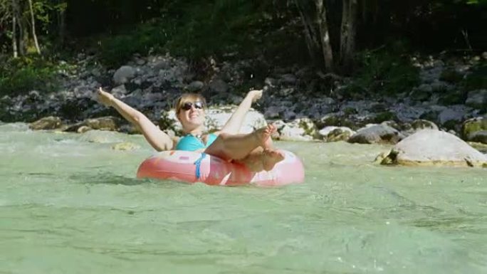 慢动作河滑翔女孩在甜甜圈漂浮物上溅水在空中