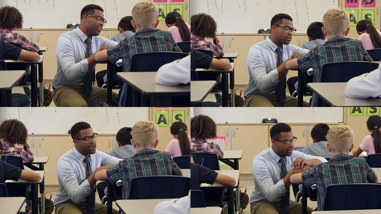 老师跪下帮助一个男孩坐在办公桌前，在R3D上拍摄