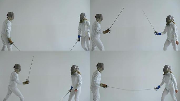 年轻女子击剑手在室内白色工作室与教练一起进行击剑训练