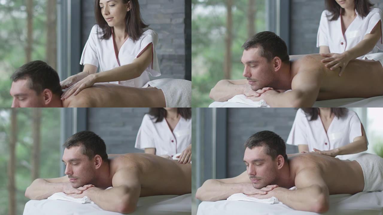 英俊的男人正在健康中心的女按摩师那里得到放松的按摩。