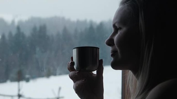 冬季，女性在度假胜地的窗户附近喝茶