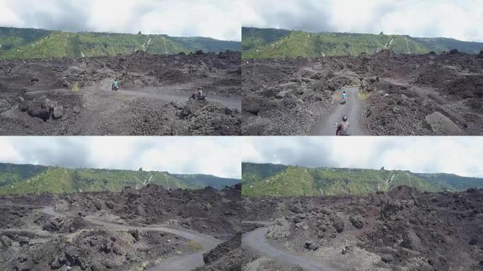 空中: 踏板车上的游客在崎volcanic的火山地形上行驶到火山边缘