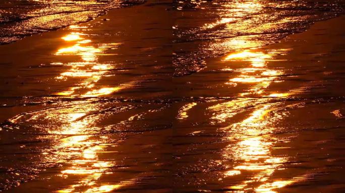 特写: 橙色的海浪在戏剧性的金色日落时冲刷着红色的沙滩
