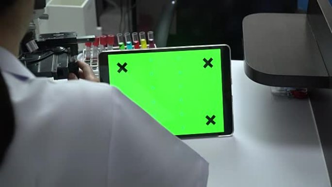 女性科学家研究和看与绿色屏幕的数字平板电脑