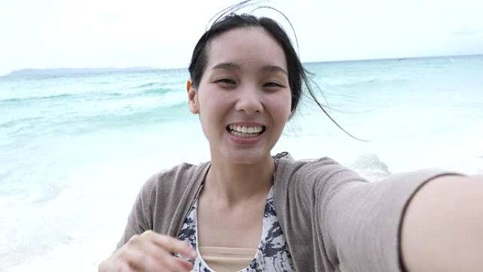 年轻女子在海滩上给她的朋友打视频电话