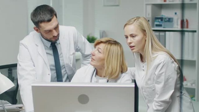医务人员在使用个人计算机时讨论与工作相关的问题。他们指向屏幕并交谈。
