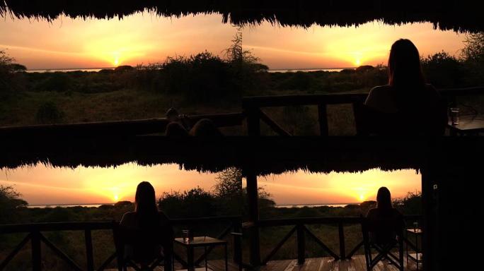 特写: 女人坐在阳台上的木椅上，看着金色的日出