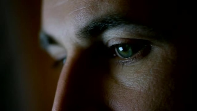 一个绿蓝男人眼睛的特写镜头，屏幕上有反射。