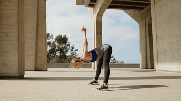 年轻健康的女人在阳光明媚的日子在外面锻炼在现代城市环境中伸展运动