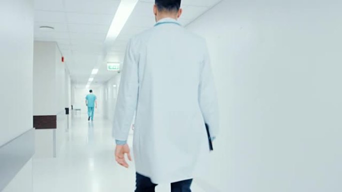 紧随其后的是一名医生匆忙穿过医院走廊的镜头。问候护士和他的同事。明亮的现代新诊所。