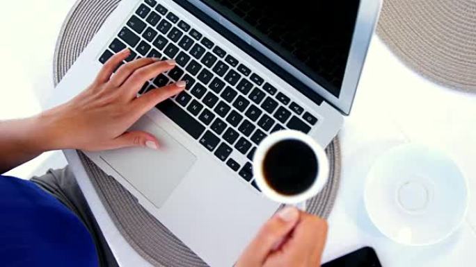 女人使用笔记本电脑并放下咖啡
