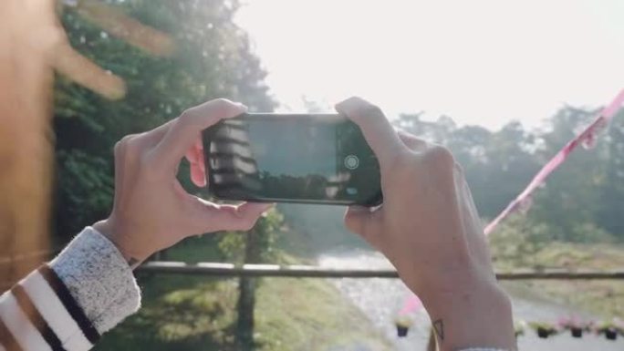 使用智能手机的女游客在早上拍摄全景照片。
