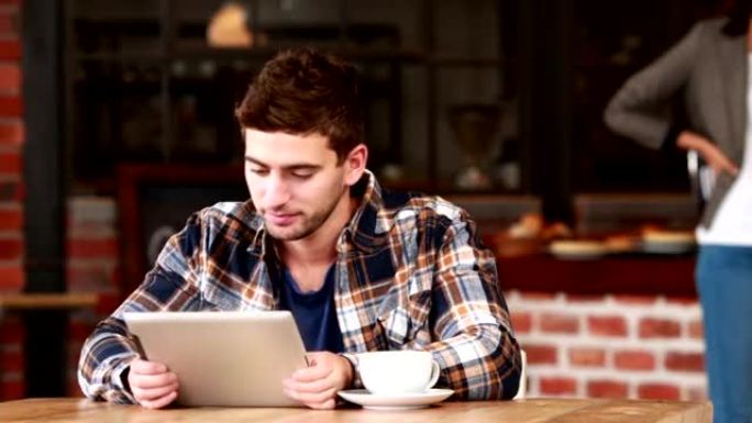 微笑的时髦男人使用平板电脑和喝咖啡