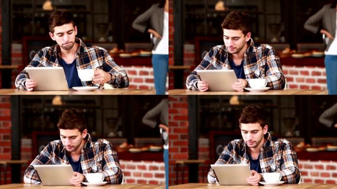 微笑的时髦男人使用平板电脑和喝咖啡