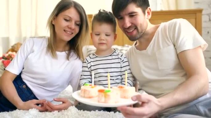 微笑的家人一起庆祝儿子生日，然后在蛋糕上吹蜡烛