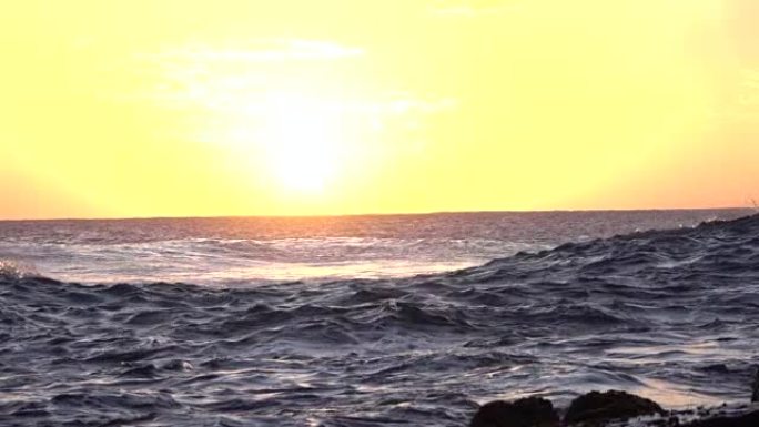 慢镜头:无尽的黑暗海洋在美丽的金色夕阳下荡漾