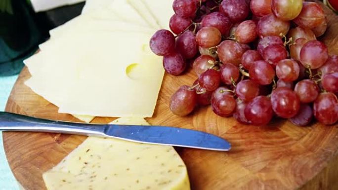 砧板上的奶酪切片，红葡萄和黄油刀