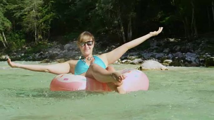 慢动作特写微笑的女人在漂浮物滑行下游溅水
