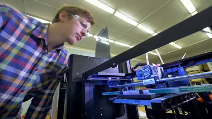 一位工程师过来查看一台大型3d打印机开始工作。4K。